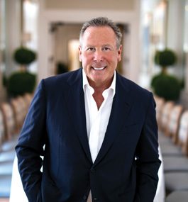 Portrait of man in white shirt and blue suit jacket standing alone in room.